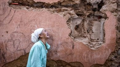 امرأة تقف أمام منزلها المتضرر من الزلزال المغرب